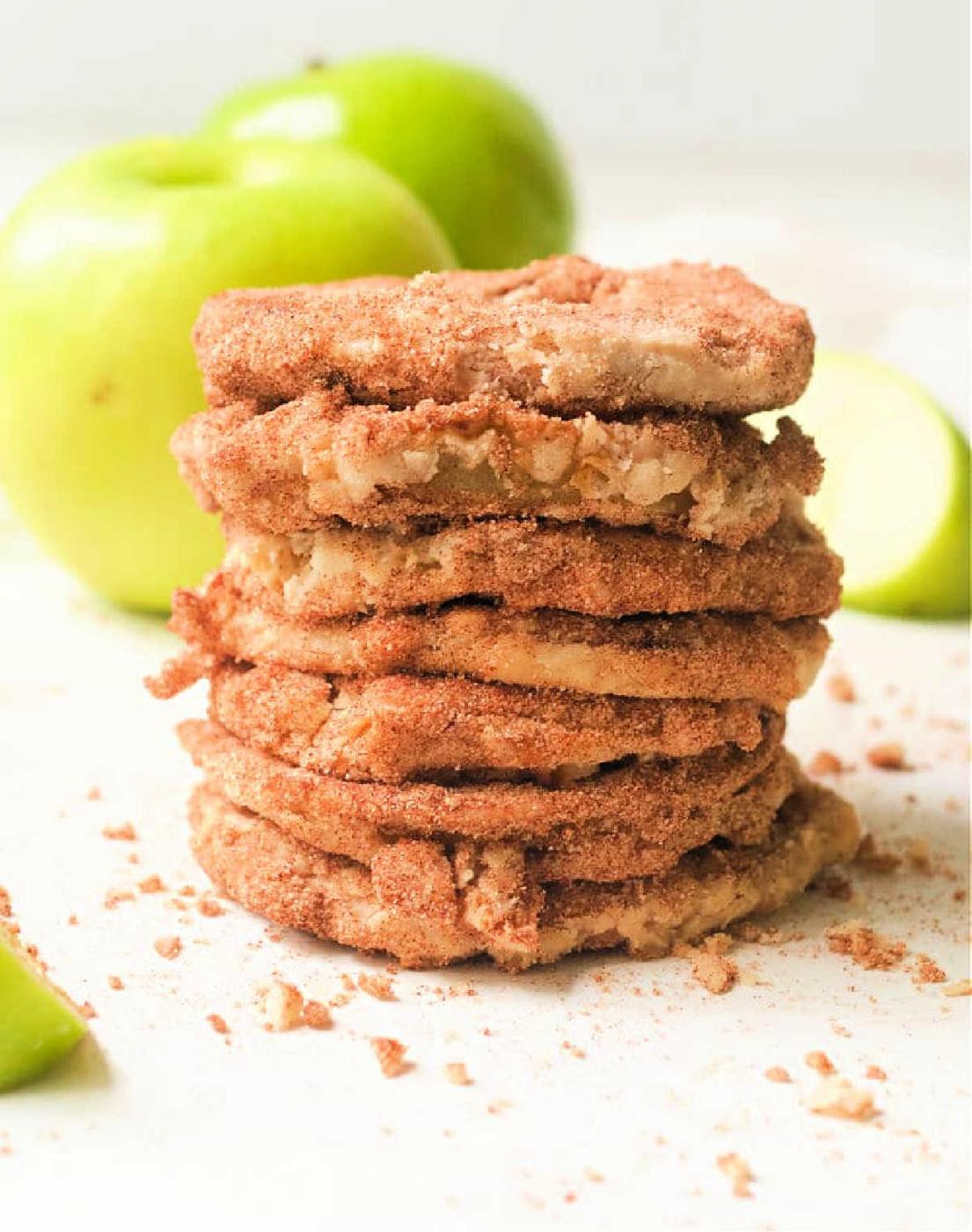 A stack of cinnamon sugar cookies with air fryer apples and green apples in the background.