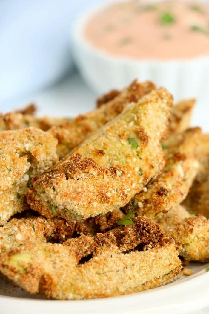 Close-up of crispy breaded artichoke hearts with a hint of air fryer artichoke hearts, accompanied by a dipping sauce in the background.