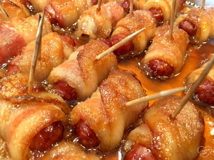 Bacon-wrapped hot dogs with toothpicks, glazed in a sticky brown sugar sauce.