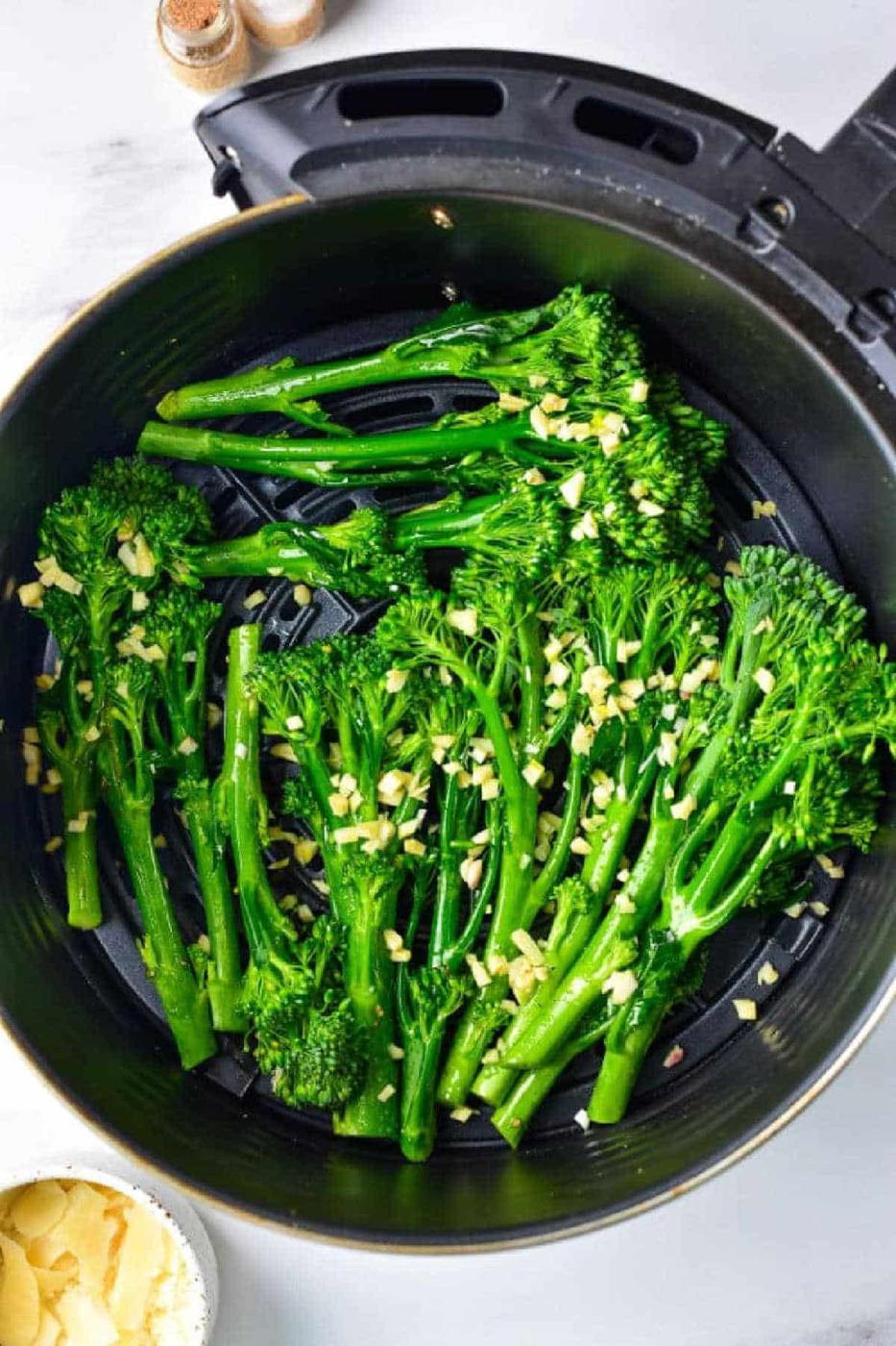 Air Fryer Broccolini with chopped garlic sits in the basket, ready to be cooked to crisp perfection.