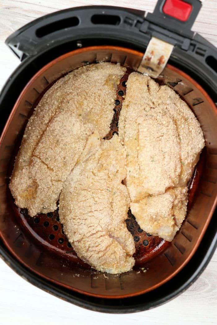 Breaded air fryer catfish fillets arranged inside the basket, ready to be cooked to crispy perfection.