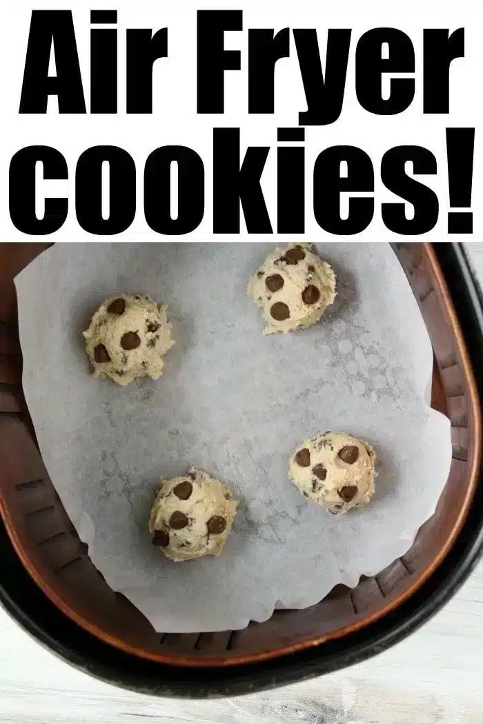 Four balls of chocolate chip cookie dough sit on parchment paper in an air fryer basket. The words “Delicious Air Fryer Cookies!” proudly top the image, promising a sweet treat.