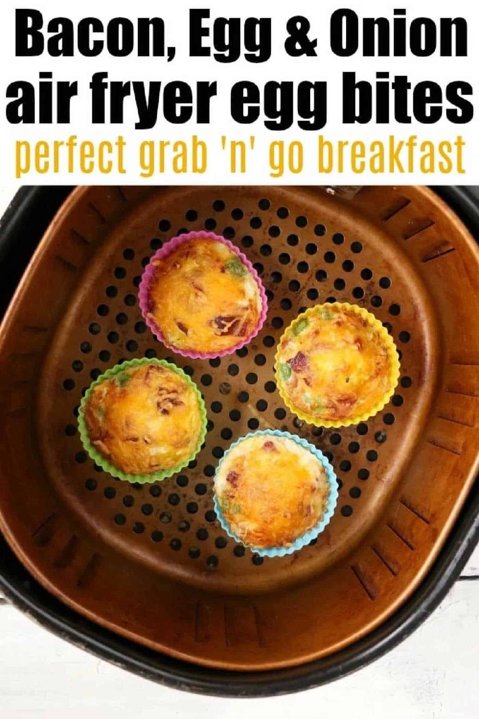 Four air fryer egg bites with bacon, egg, and onion sit in colorful silicone cups inside an air fryer basket.
