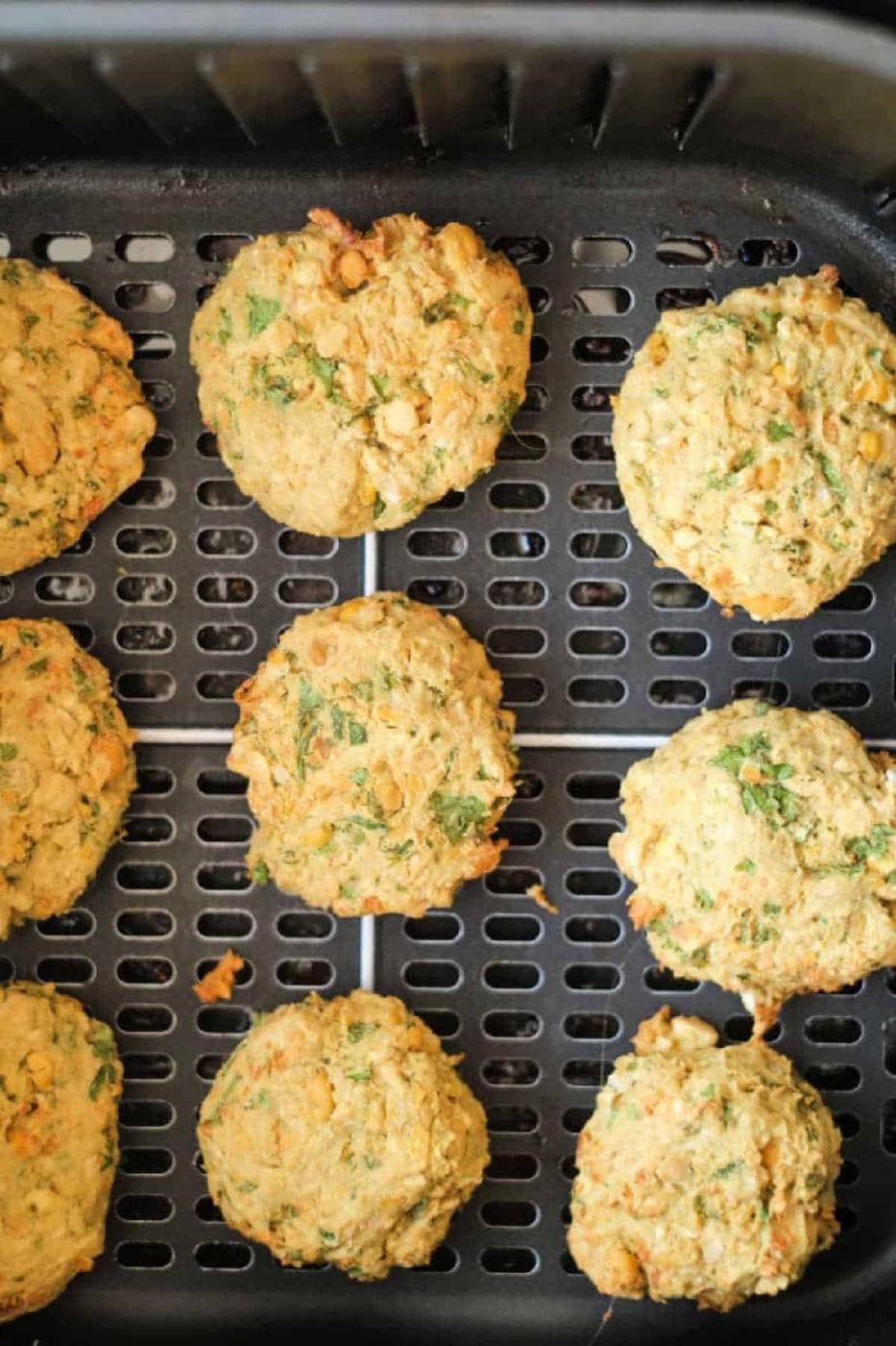 Nine air fryer falafel patties on a tray, golden brown and flecked with herbs.