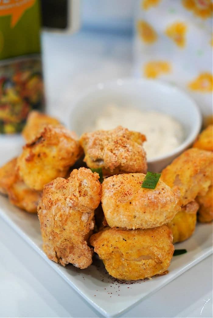 A plate of crispy, breaded chicken nuggets sits beside a bowl of dipping sauce, perfect for snacking—try swapping in air fryer fish nuggets for a tasty twist.
