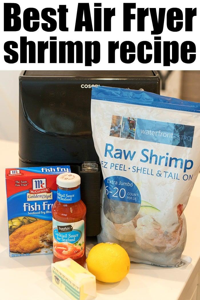 An air fryer sits on a countertop surrounded by ingredients for delicious fried shrimp: a bag of raw shrimp, fish fry seasoning, cocktail sauce, lemon, and butter. Text reads Best Air Fryer Fried Shrimp Recipe.
