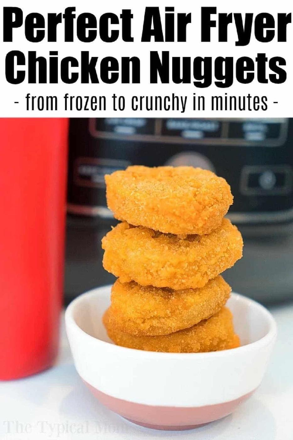 Four golden air fryer frozen chicken nuggets stacked in a bowl, with an air fryer in the background.