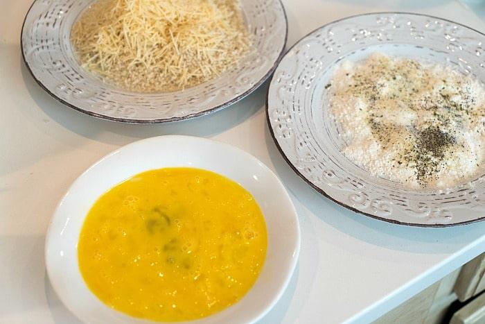 On the table sat three dishes: grated cheese, a flour mixture with pepper, and beaten eggs, all ready to coat the Air Fryer Green Bean Fries to perfection.