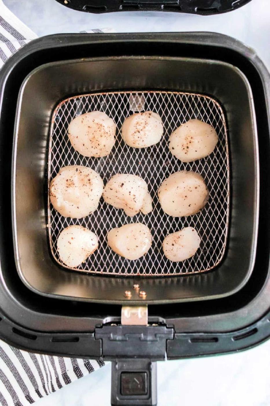 Air fryer scallops are seasoned with pepper and arranged in a single layer inside the air fryer basket for perfect, tender results.