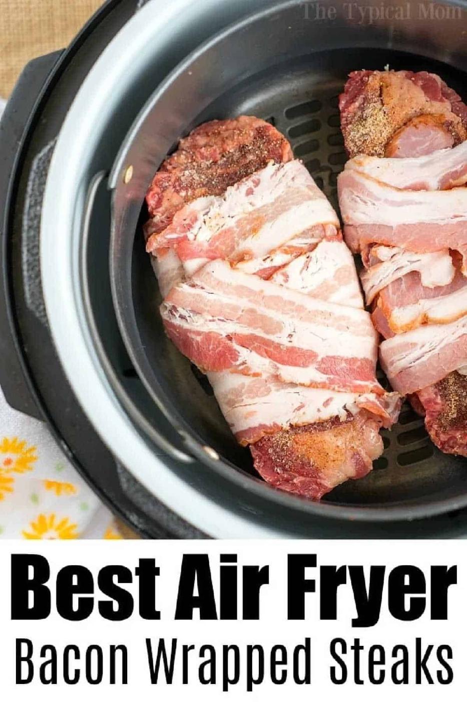 Two raw bacon-wrapped air fryer steaks sit in the basket, ready to cook.