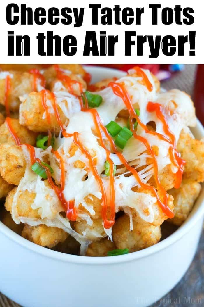 Bowl of crispy air fryer tater tots topped with melted cheese, hot sauce, and chopped green onions.