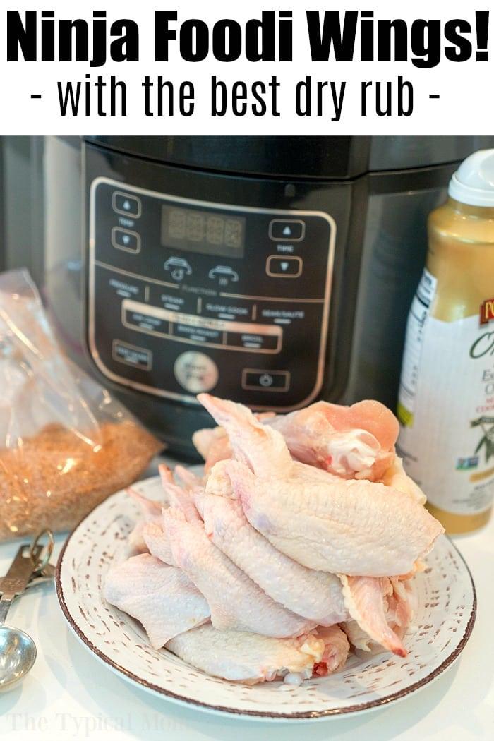 A plate of raw chicken wings awaits the Ninja Foodi air fryer, ready to become the ultimate air fryer wings recipe. A packet of seasoning and a bottle of mustard sit nearby, promising flavor perfection. The text above reads, "Ninja Foodi Wings! - with the best dry rub -".