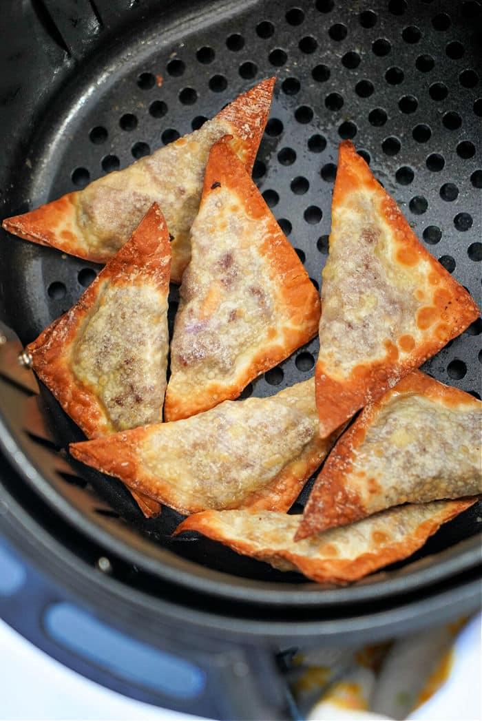 Air-fried crispy won tons are perfectly arranged in a sleek black air fryer basket.
