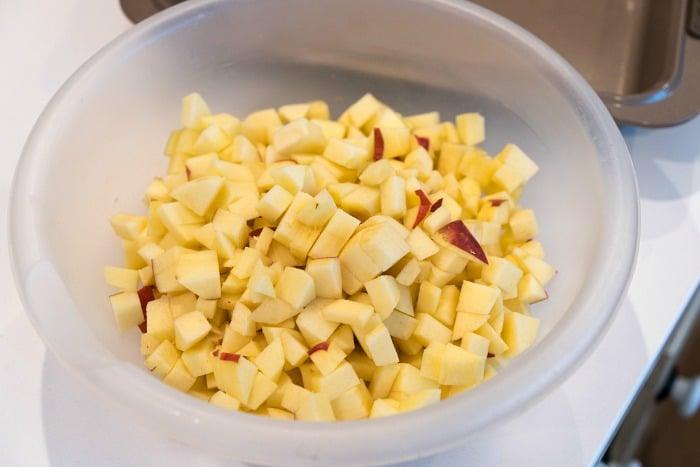 A bowl filled with diced apples rests on a white countertop.