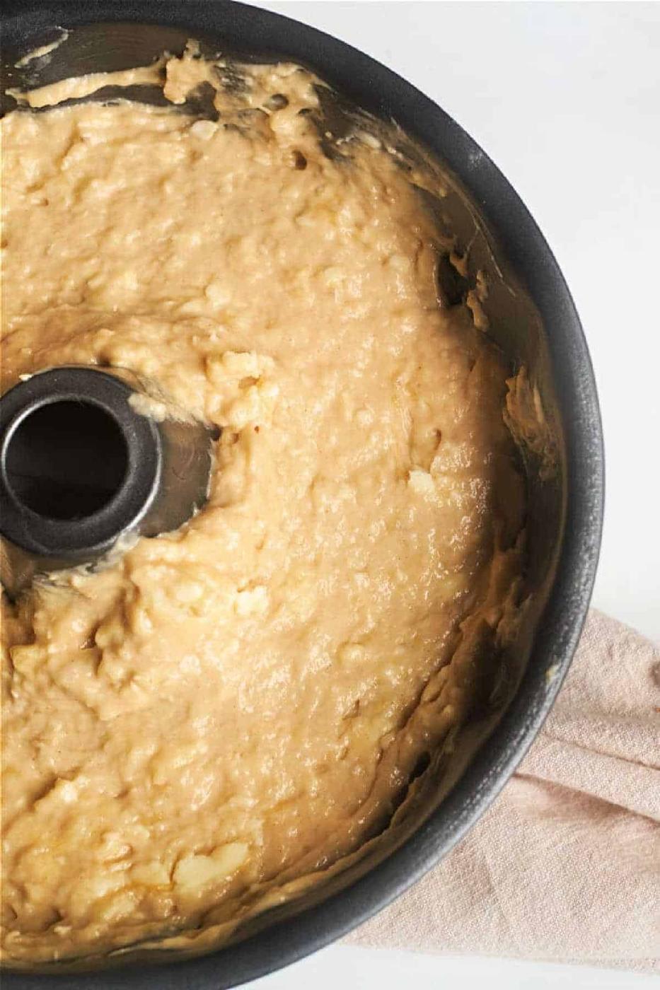 Banana Bread Bundt Cake batter with visible banana pieces in a bundt cake pan, ready to be baked.