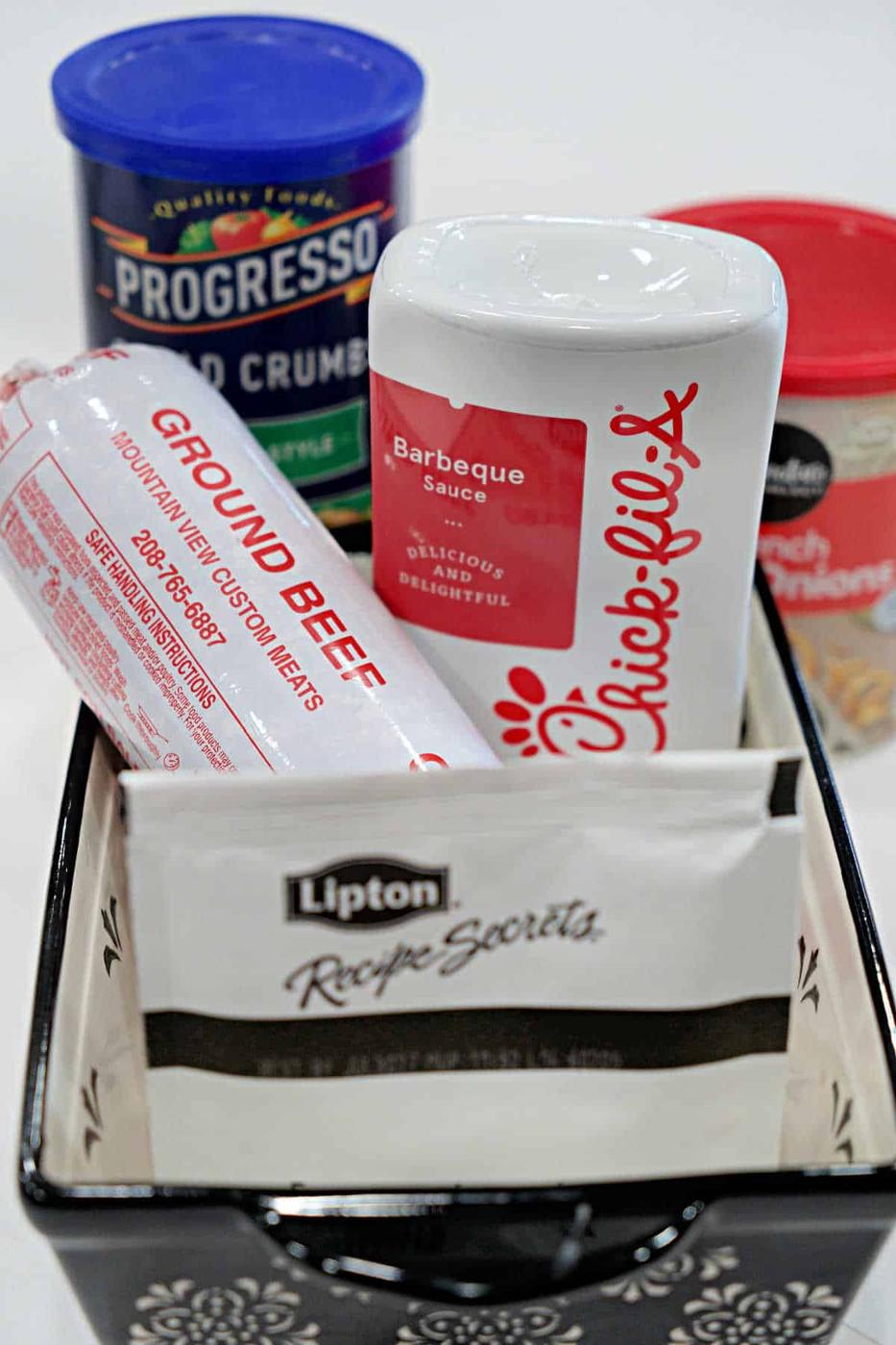 A basket with ground beef, Chick-fil-A sauce, Lipton soup mix, bread crumbs, and cream of chicken soup—everything you need for a delicious BBQ Meatloaf Recipe.