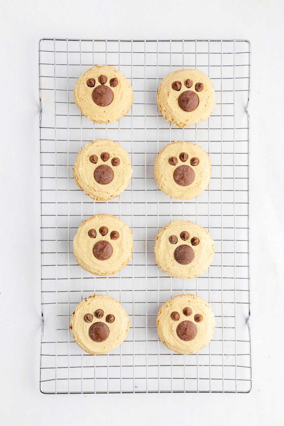 Eight butter pecan Cookies with paw print designs rest on a cooling rack, viewed from above on a white background.