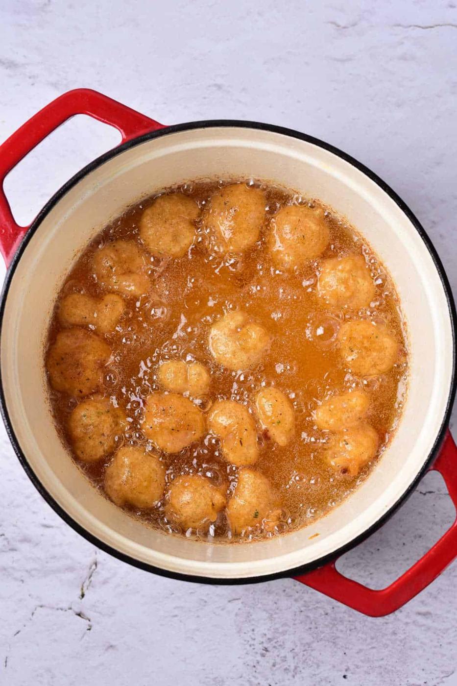 Golden-brown shrimp, crisp from their beer batter, sizzle in a red-handled pot filled with bubbling oil.