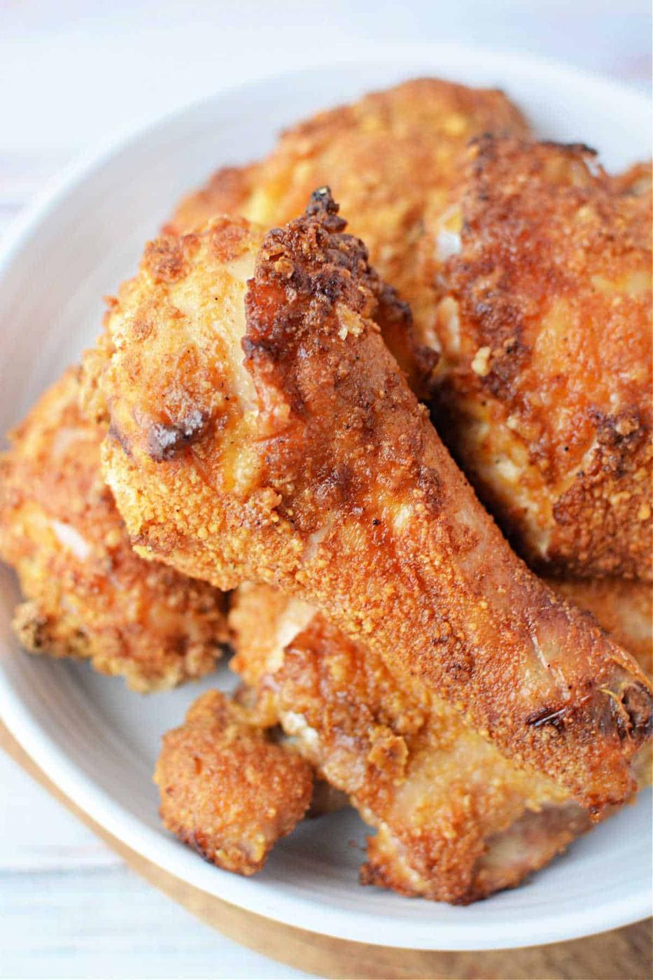 A plate of golden-brown Bisquick oven-fried chicken drumsticks and thighs.