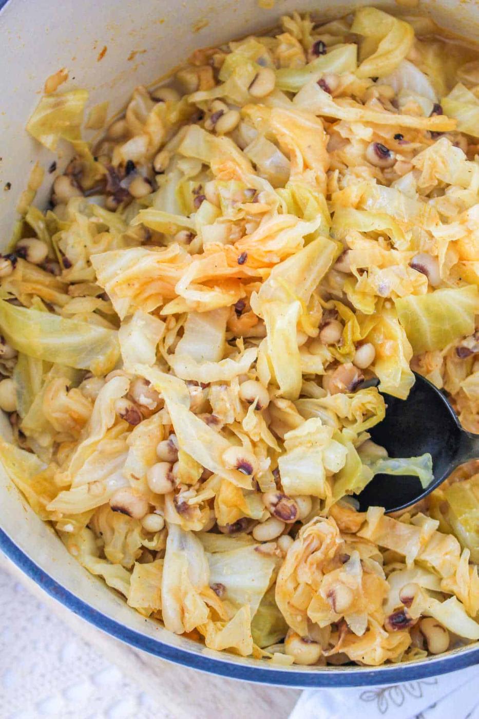 A savory pot of Black Eyed Peas and Cabbage awaits, complete with a spoon.