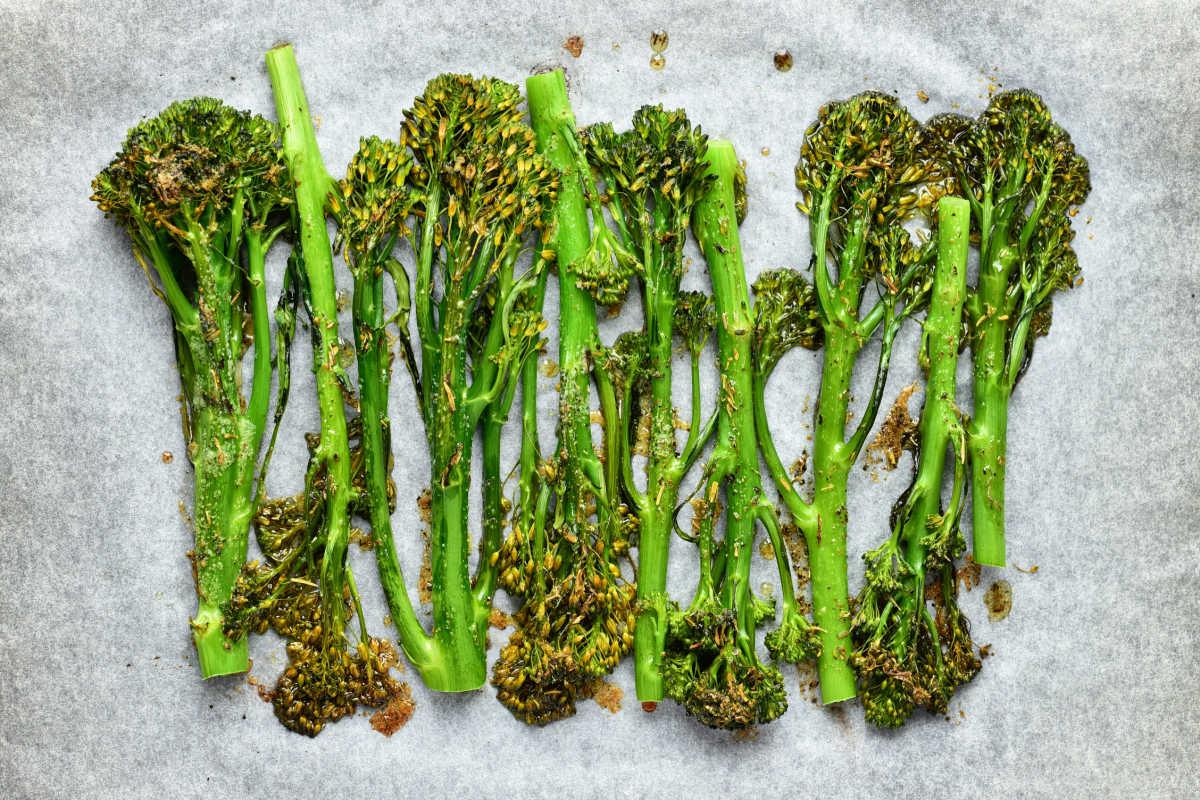 Oven roasted broccolini arranged on parchment paper, perfectly lightly browned and seasoned for a flavorful bite.