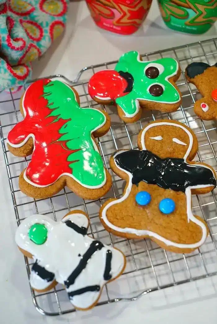 Colorful, decorated cake mix gingerbread cookies in various shapes rest on a cooling rack.