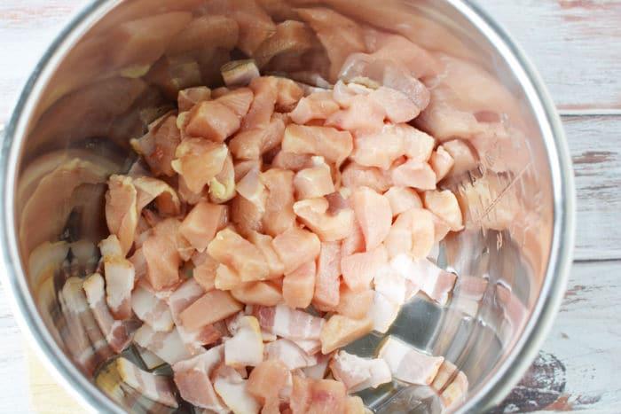 Diced raw chicken and bacon pieces in a stainless steel mixing bowl, ready to be the flavorful base for Chicken Crack Soup.