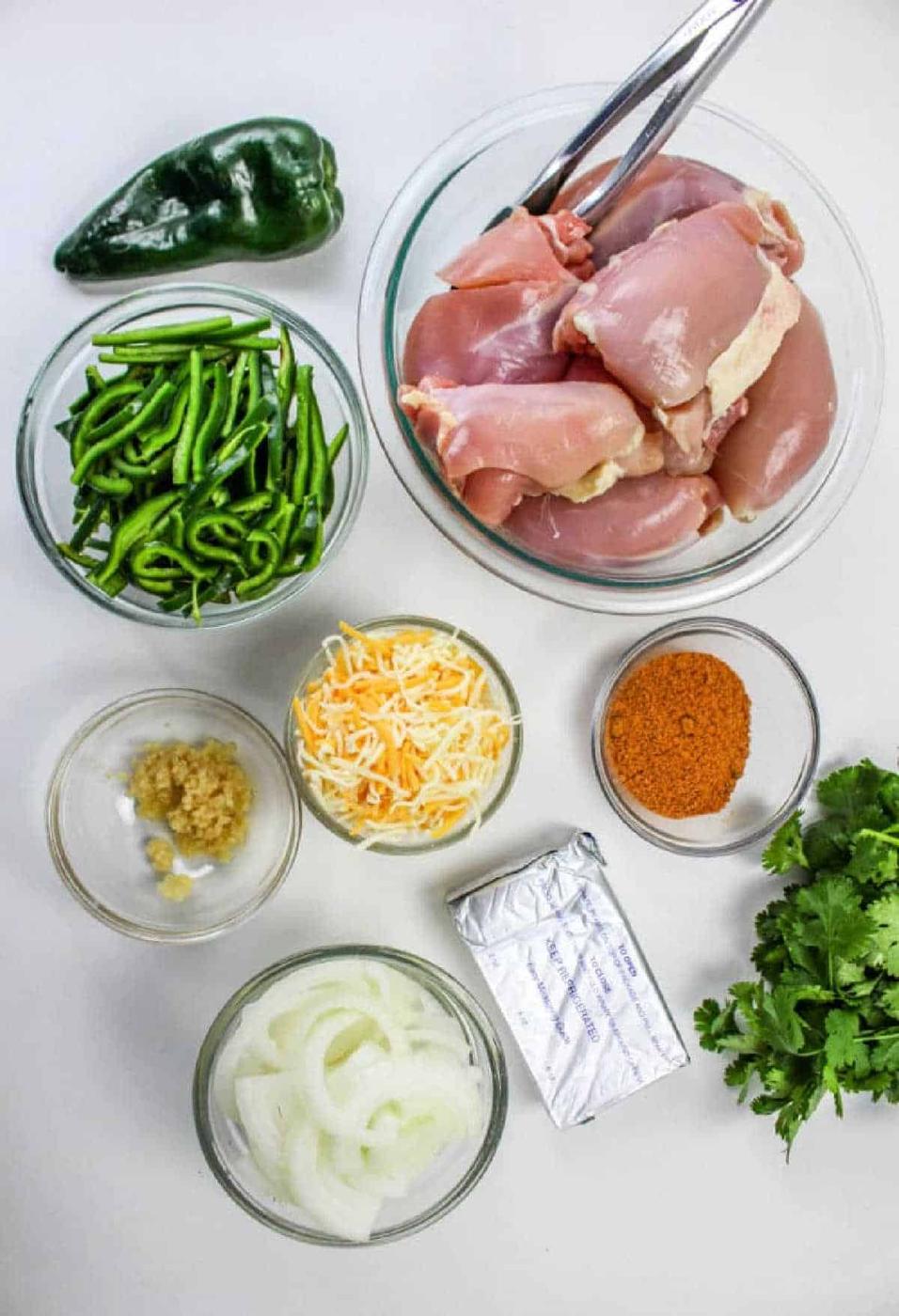 Ingredients for Chicken Poblano: raw chicken, poblano peppers, cheese, spices, onion, cream cheese, garlic, and cilantro—perfect for a flavorful meal.