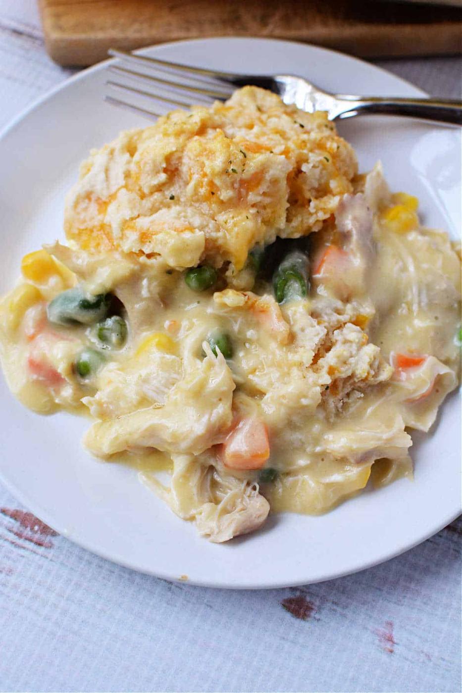 A plate of creamy chicken and vegetable casserole, reminiscent of Chicken Pot Pie, topped with a flaky Red Lobster Biscuit, with a fork on the side.