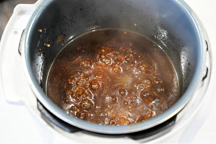 A pot of dark, bubbling liquid is simmering in a pressure cooker ready for drippings to be made into gravy