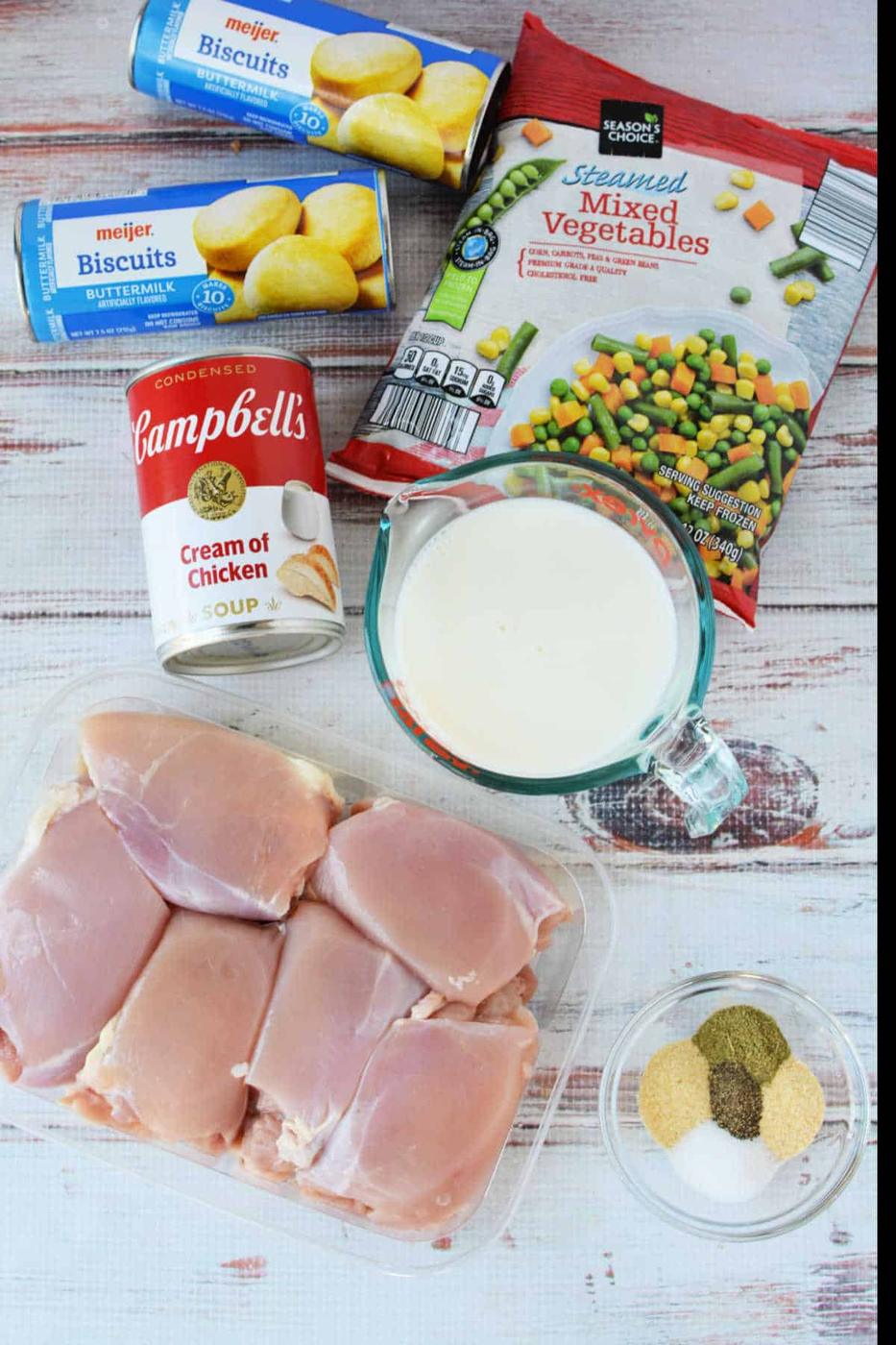 Ingredients for a Chicken Pot Pie casserole: biscuits, frozen mixed vegetables, cream of chicken soup, milk, chicken, and spices—perfect for baking or making in your Crockpot.