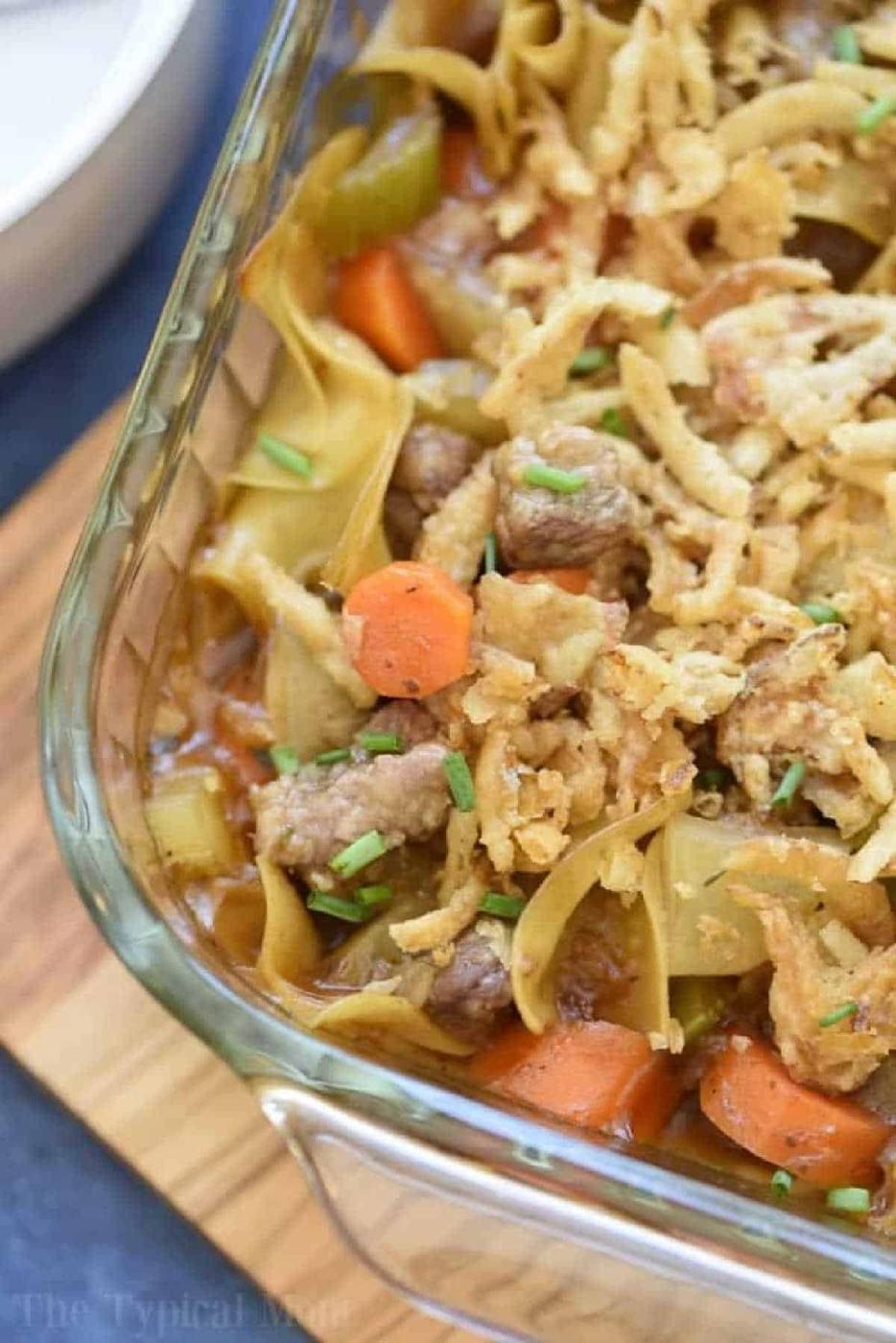 Easy beef stew casserole with carrots, celery, and crispy fried onions in a glass baking dish.