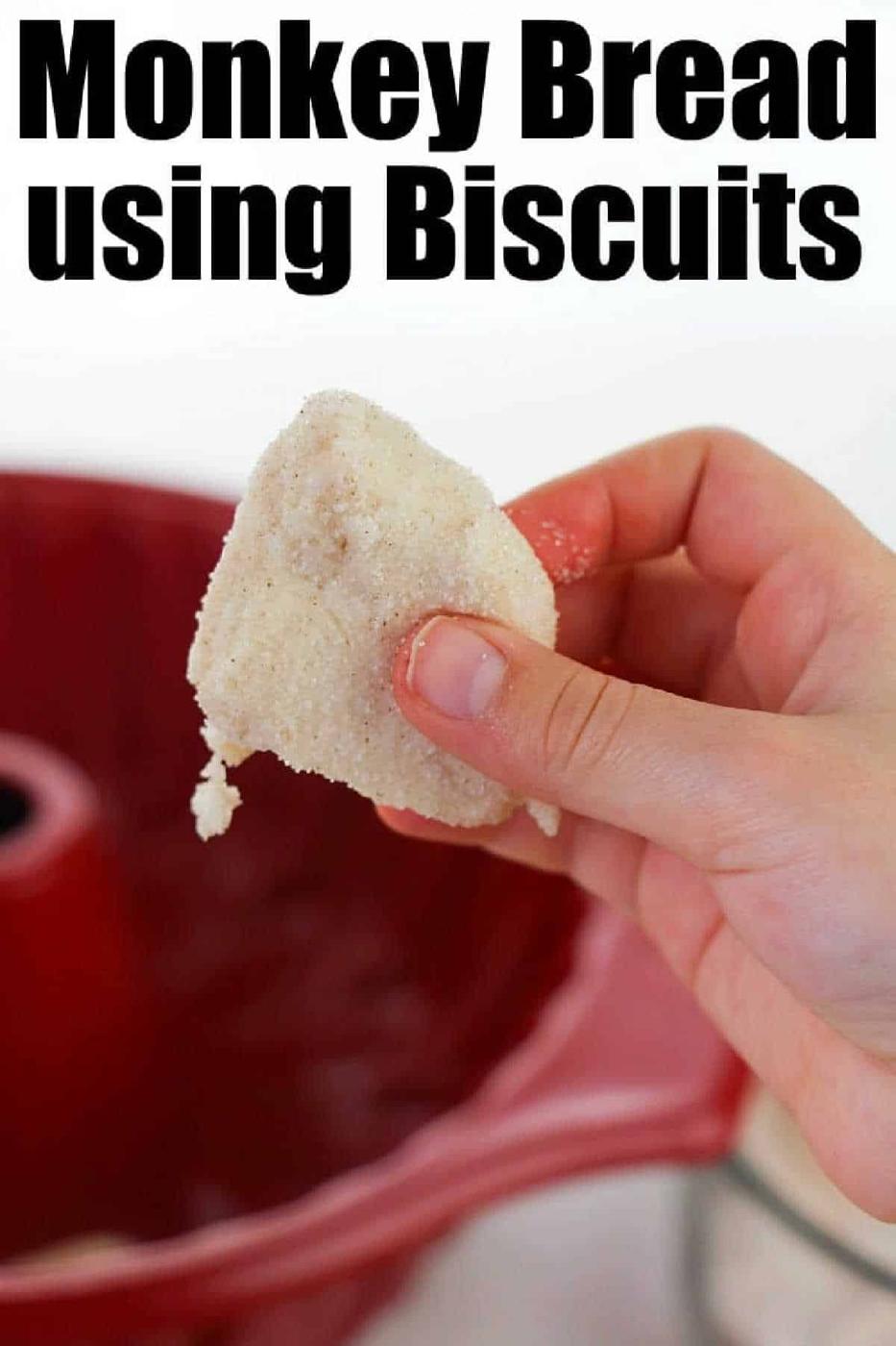 A hand holds a sugar-coated biscuit in front of a red bundt pan; text reads Easy Monkey Bread Recipe using Biscuits.