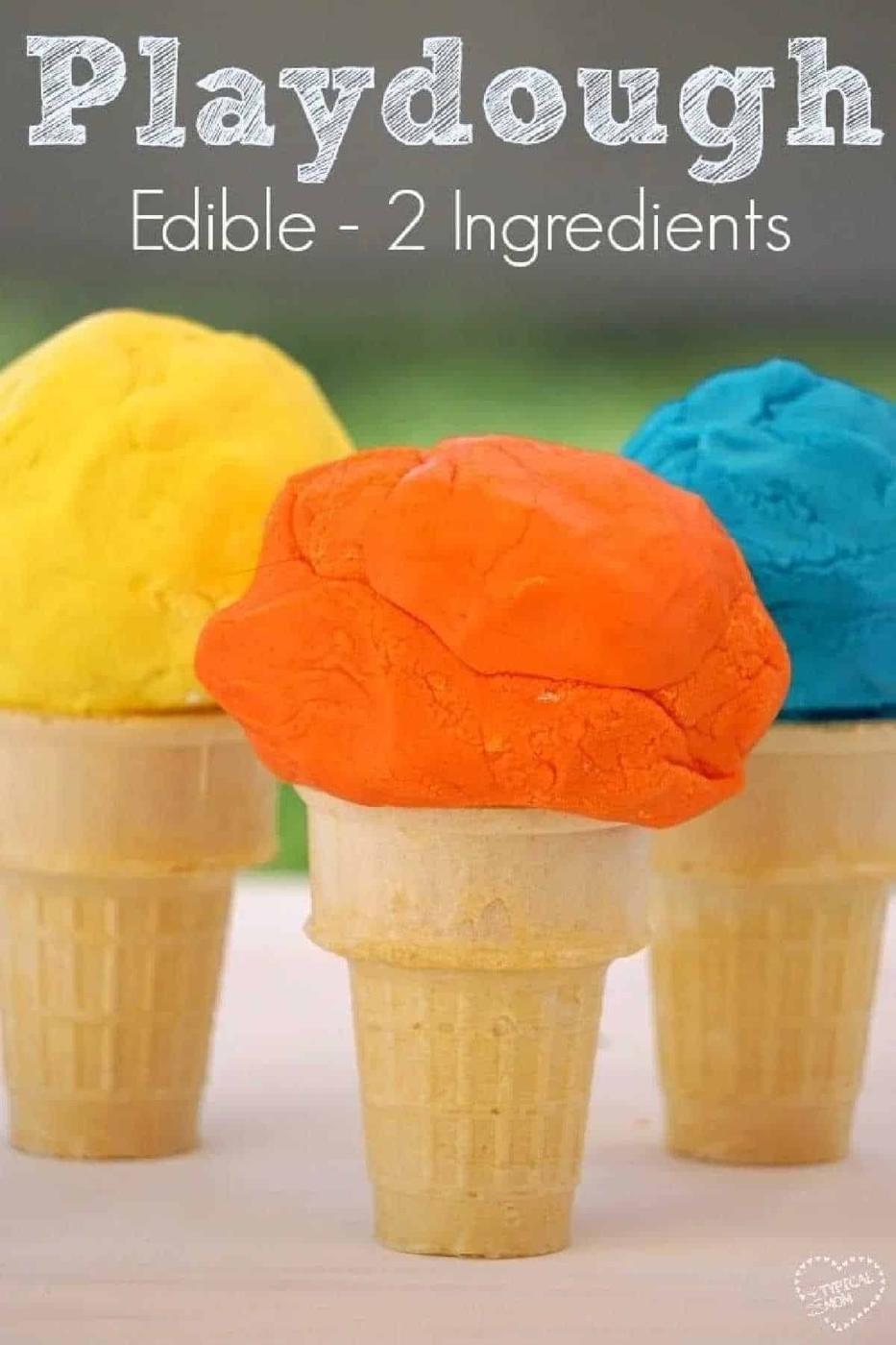 Three ice cream cones topped with colorful scoops of edible playdough in yellow, orange, and blue sit on a table.