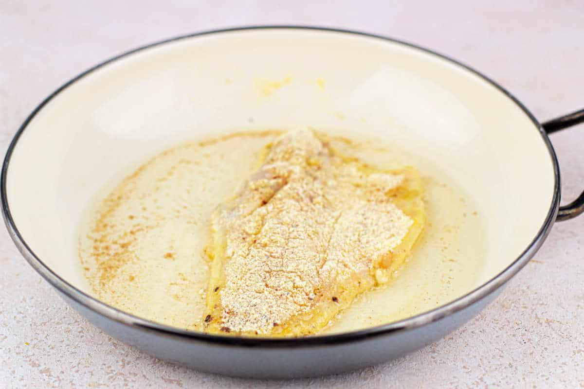 Fried Swai Fish fillet, perfectly coated in corn flour, sizzles in a butter-filled pan.