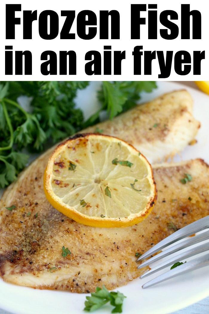 Cooked fish fillet on a plate, delicately topped with a lemon slice and garnished with parsley, while a fork rests beside it. Experience tender perfection by preparing your frozen fish in an air fryer.