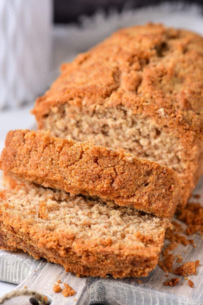 Sliced healthy coffee cake, rests on a wooden board, crumbs artfully scattered around.