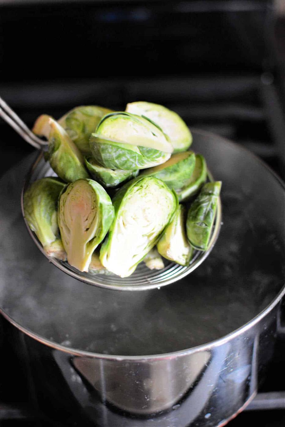 Brussels sprouts in a strainer over a pot of boiling water on the stove, just enough to infuse them with that perfect tender-crisp texture. Curious about how long to boil Brussels sprouts for delicious results? Keep an eye on them and achieve perfection in just a few minutes.