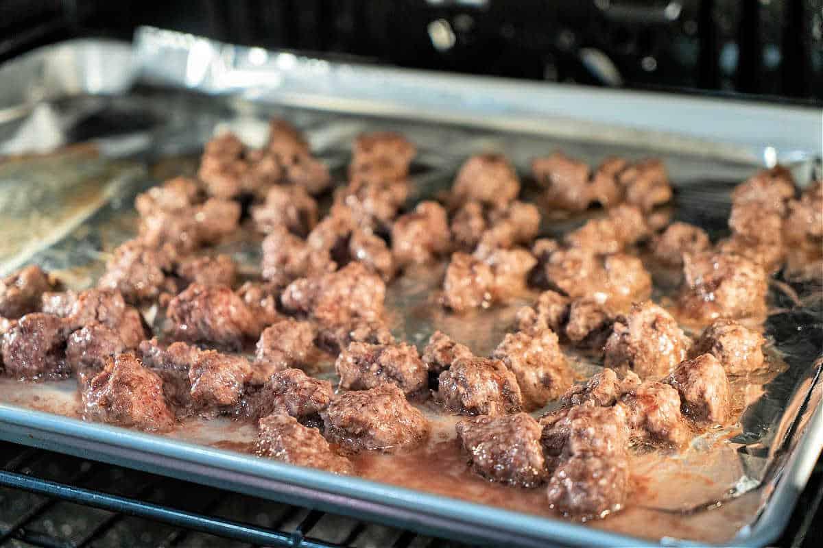 ground beef sizzle on a foil-lined baking sheet in the oven, turning golden brown. It's crucial to know how long to cook ground beef for perfect doneness and flavor, ensuring a juicy delight every time.