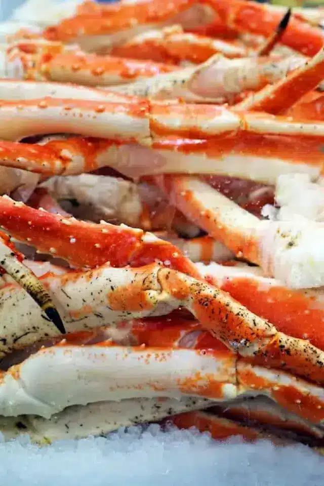 A close-up view of a pile of red and white crab legs on ice, showcasing their texture and colors.