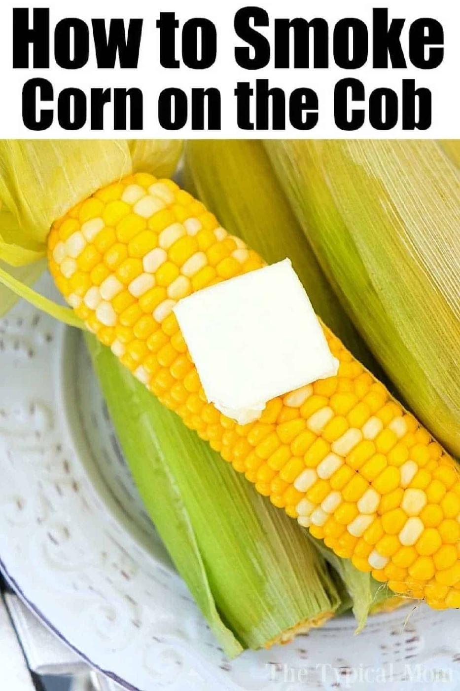 Corn on the cob with a pat of butter and husks, served on a white plate. Discover how to smoke corn on the cob for extra flavor. Text: How to Smoke Corn on the Cob.