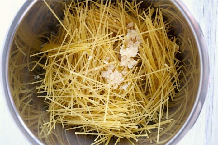 Spaghetti noodles and minced garlic mingle effortlessly in the instant pot, creating a delightful base perfect for pairing with tangy bang bang shrimp.