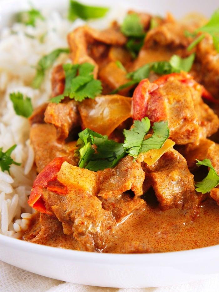 A plate of butter beef with bell peppers, prepared in an Instant Pot, served with white rice and garnished with fresh cilantro.