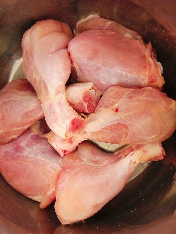 Raw chicken legs, sit in a metal bowl, ready for instant pot cooking or preparation.