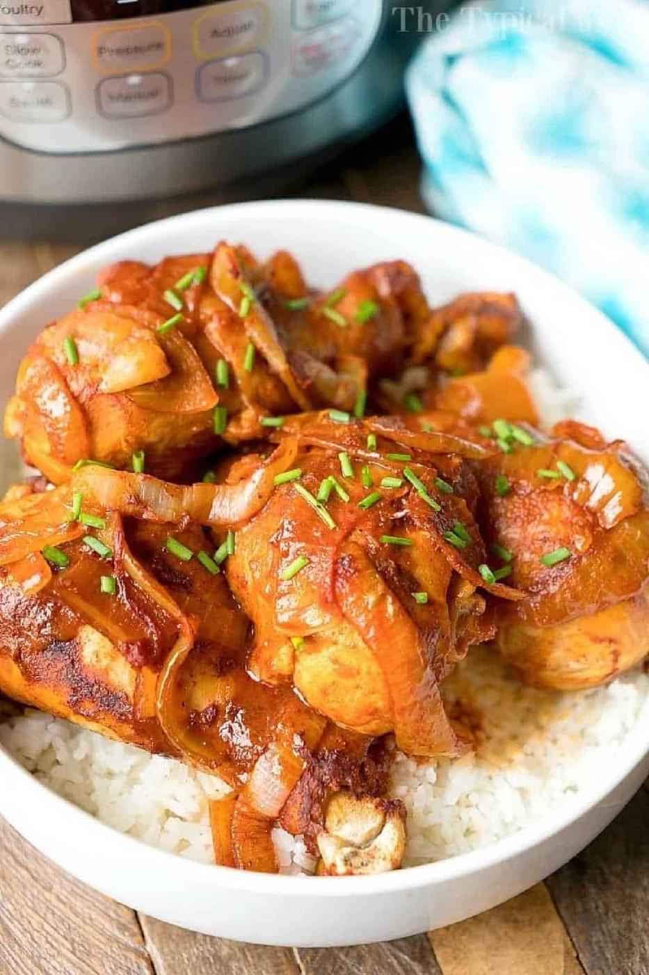 Instant Pot chicken legs cooked with onions and savory sauce, served over white rice in a bowl, with an Instant Pot in the background.