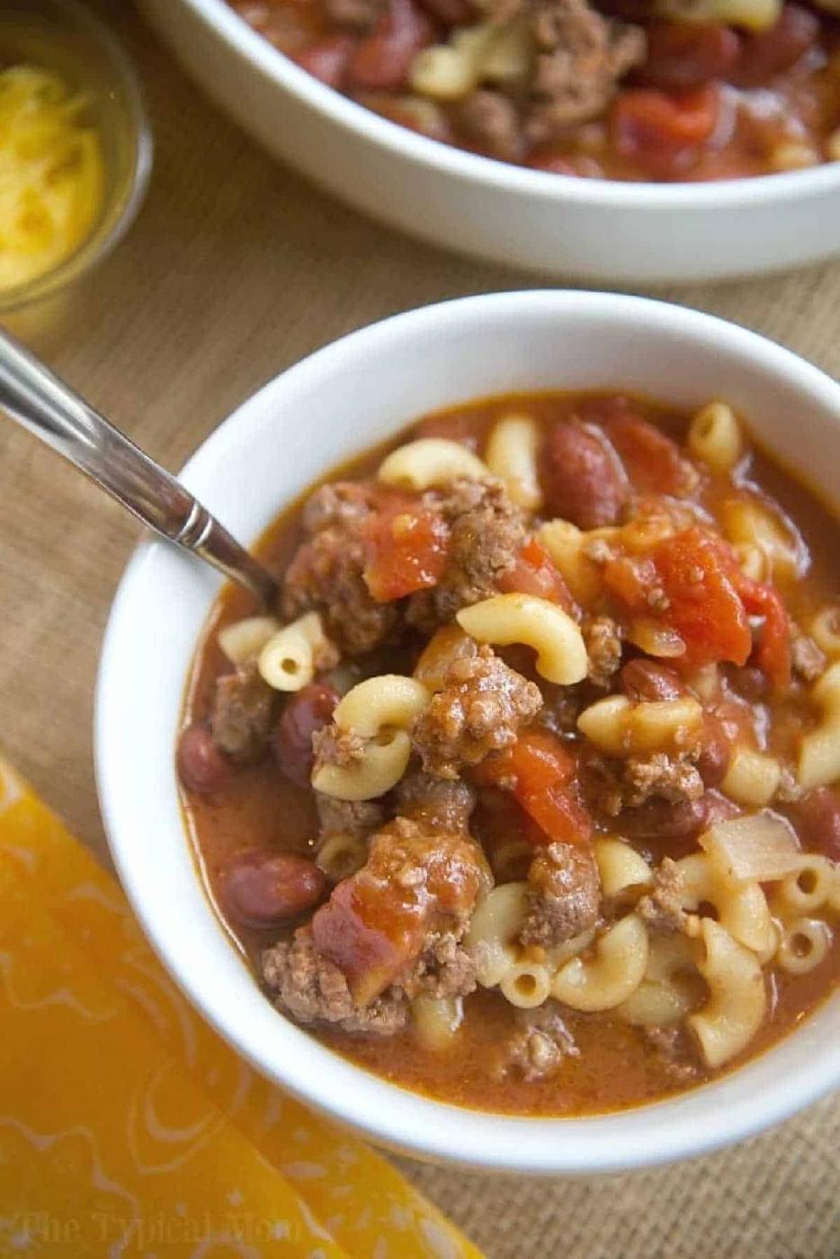 A bowl of goulash featuring macaroni, ground beef, tomatoes, and beans, with a spoon in the bowl—perfect for those craving an easy instant pot chili mac recipe.