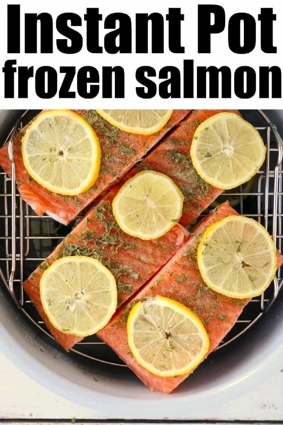 Four pieces of instant pot frozen salmon topped with lemon slices and herbs, arranged in the basket and ready to cook.