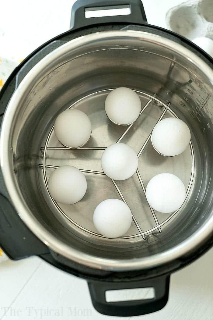 Top-down view of six white eggs on a trivet inside an electric pressure cooker, ready for a colorful twist—perfect prep before you learn how to dye eggs with Kool-Aid.