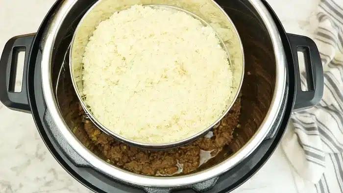 Overhead view of rice in a bowl stacked over instant pot Korean beef on a marble surface.