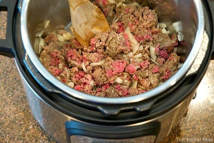 Ground beef and chopped onions are being cooked to perfection in an Instant Pot